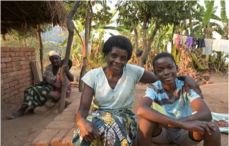 Chimwemwe sitzt mit seiner Mutter vor ihrem Haus.